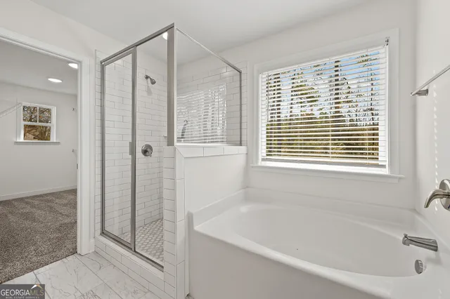 a bathroom with a bathtub a shower and a window