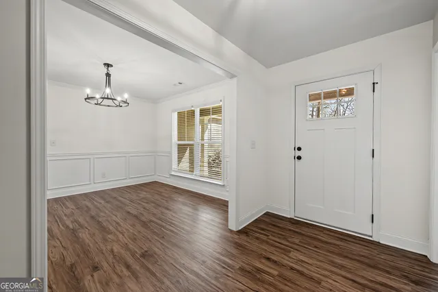 an empty room with wooden floor closet and windows