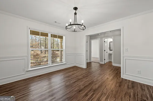a view of an empty room with wooden floor and windows