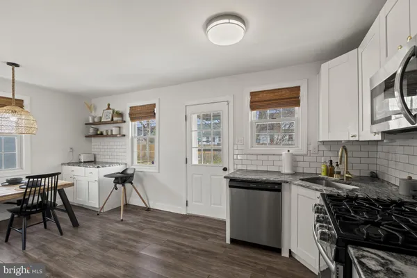 a kitchen with granite countertop a sink appliances cabinets and wooden floor