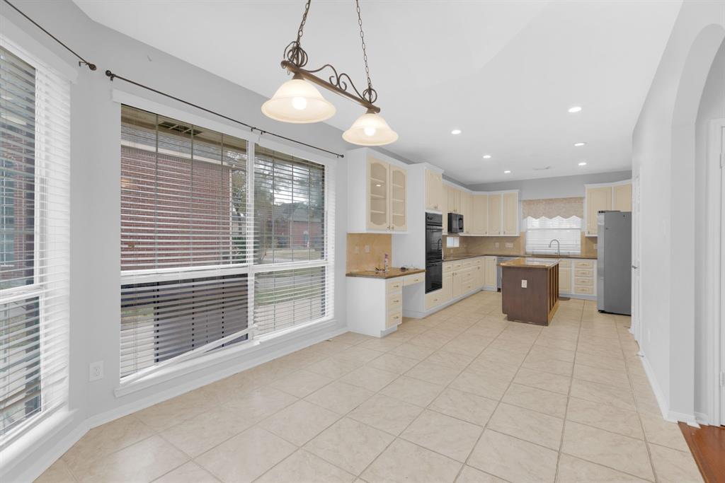 3714 Cedar Glen Lane Spring, TX 77388 - Photo 14 of 29 Kitchen with glass fronted cabinets, decorative light fixtures, backsplash, light tile patterned flooring, and a center island