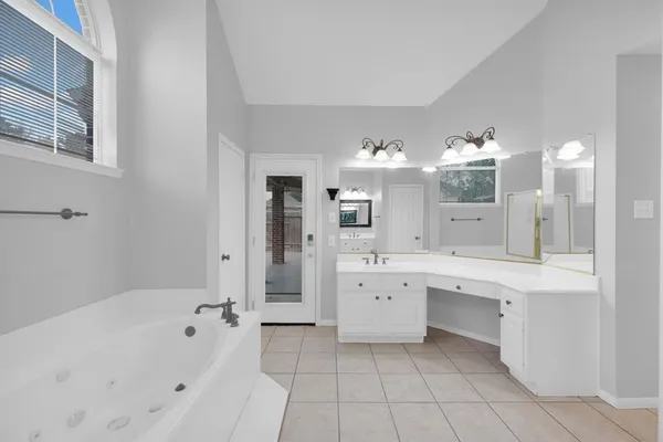 a large bathroom with a tub sink and mirror
