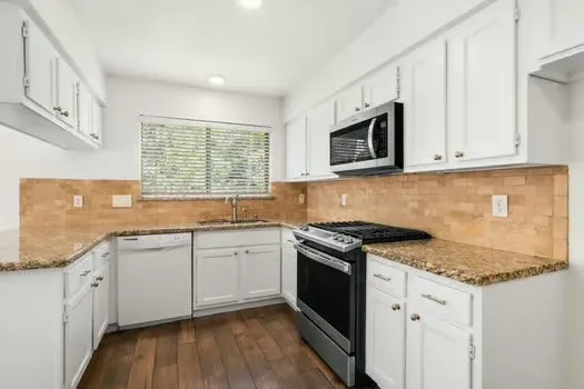a kitchen with stainless steel appliances granite countertop a stove a sink and a microwave