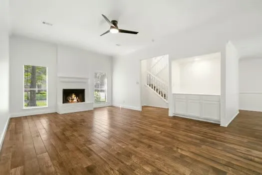 an empty room with wooden floor fireplace and windows