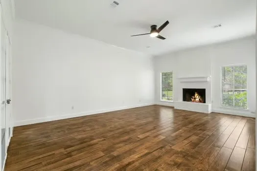 an empty room with wooden floor fireplace and windows