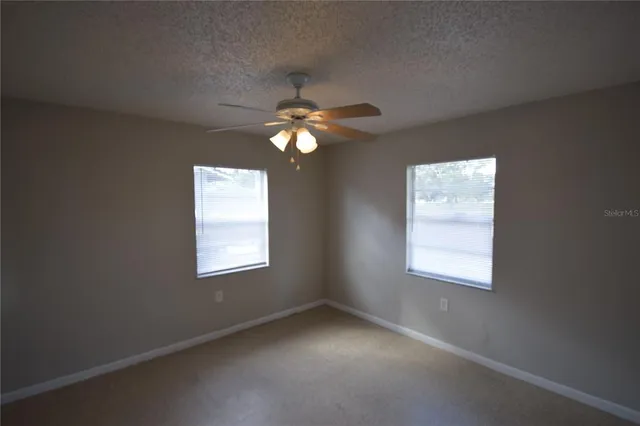 an empty room with windows and fan