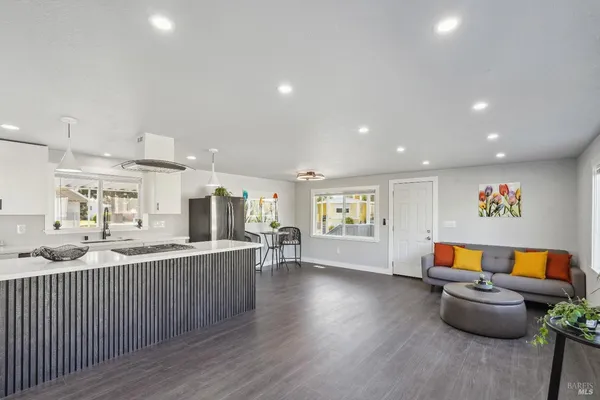 a kitchen with a stove a sink a refrigerator and white cabinets with wooden floor