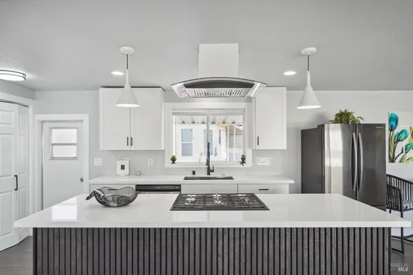 a kitchen that has a sink a refrigerator a stove and white cabinets with wooden floor
