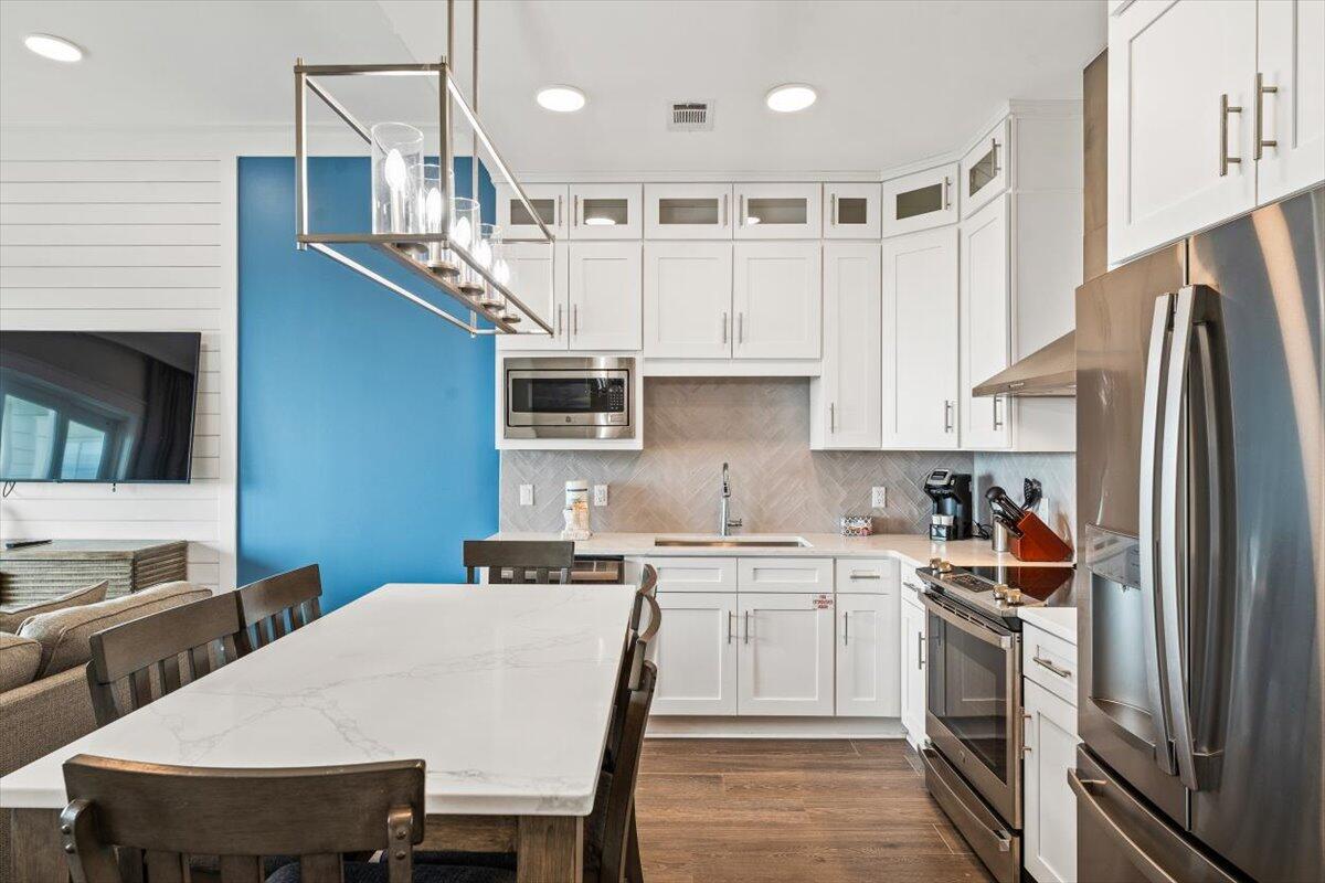 206 Henderson Resort Way, Unit 5403 Destin, FL 32541 - Photo 3 of 41 a kitchen with stainless steel appliances granite countertop a sink a stove a refrigerator a microwave oven with white cabinets and wooden floor