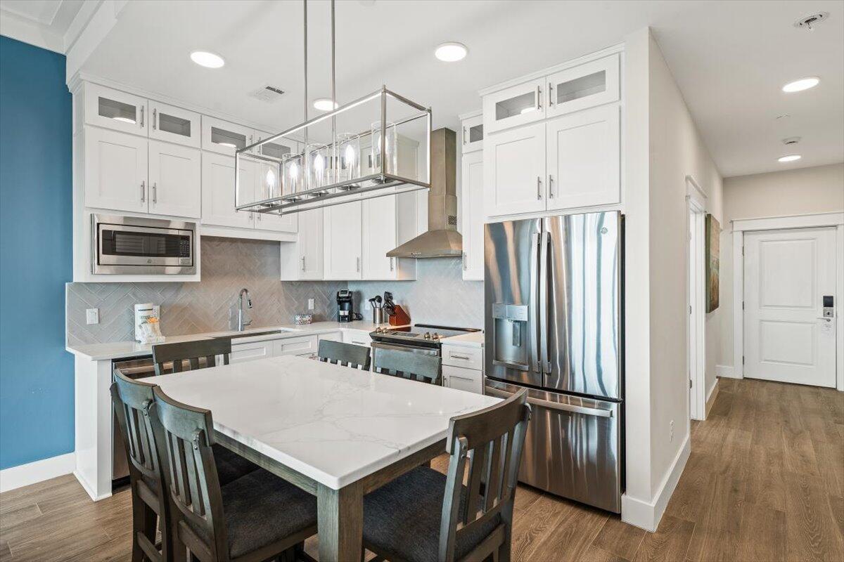 206 Henderson Resort Way, Unit 5403 Destin, FL 32541 - Photo 4 of 41 a kitchen with stainless steel appliances a table chairs refrigerator and microwave