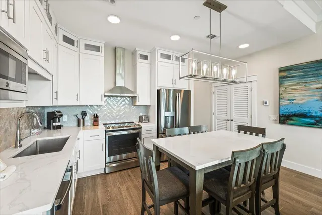 a kitchen with stainless steel appliances granite countertop a stove a refrigerator a kitchen island a dining table and chairs