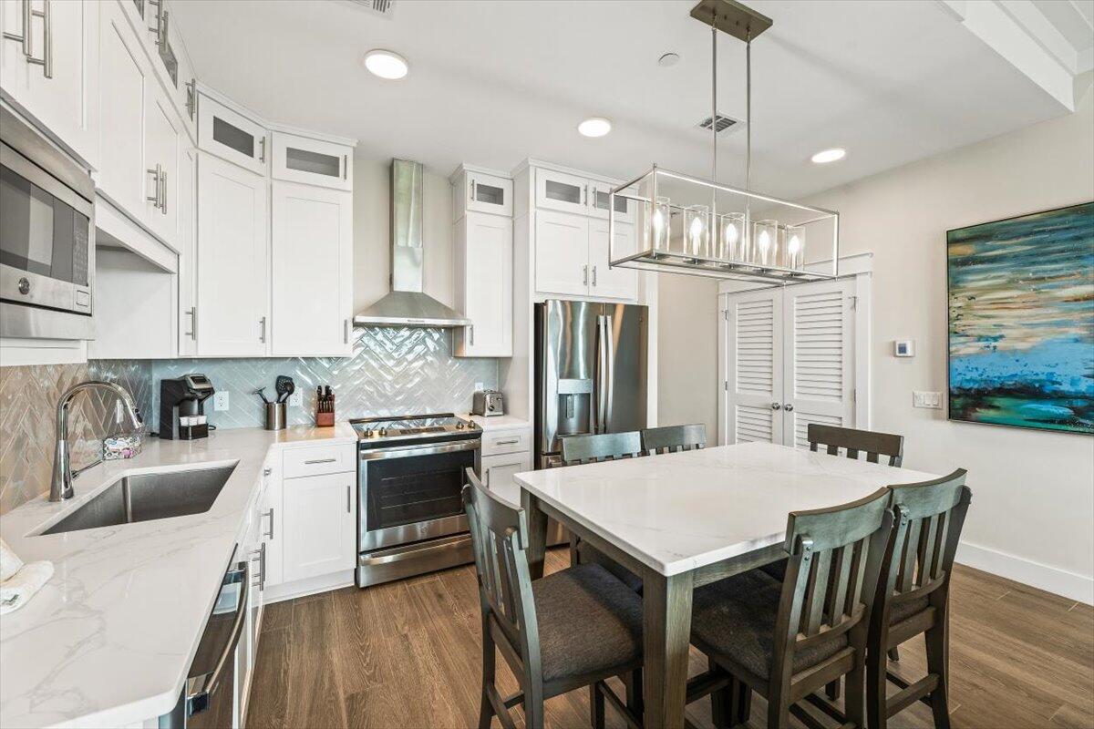 206 Henderson Resort Way, Unit 5403 Destin, FL 32541 - Photo 5 of 41 a kitchen with stainless steel appliances granite countertop a stove a refrigerator a kitchen island a dining table and chairs