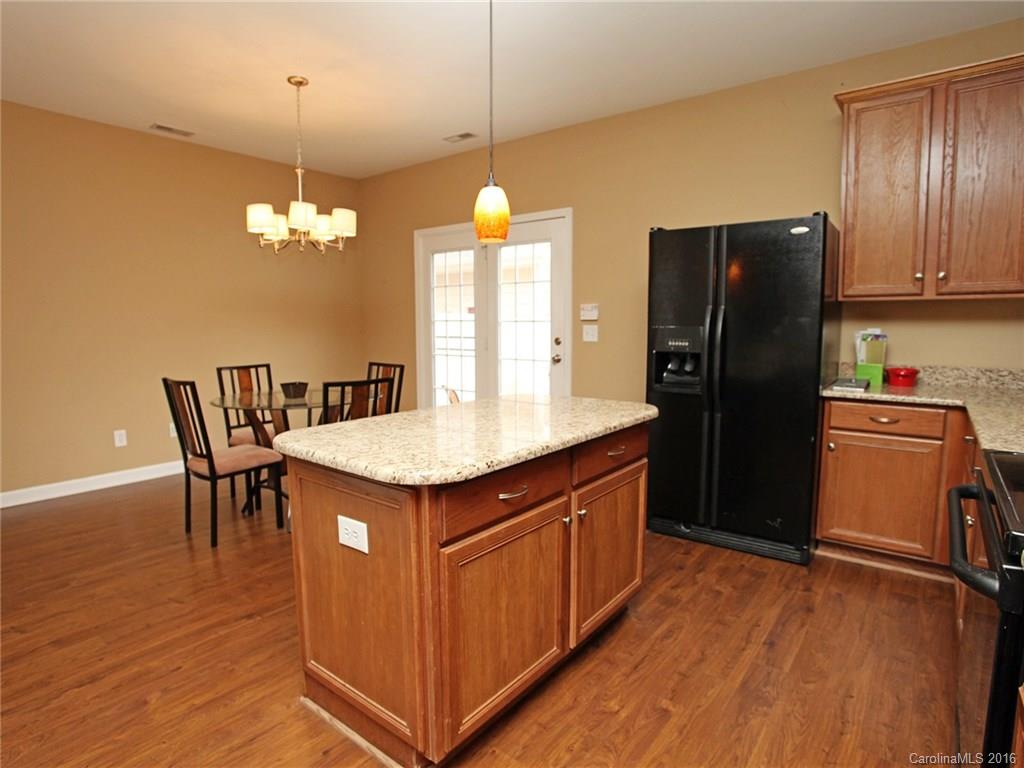 1050 Market Street, Unit 1050 Fort Mill, SC 29708 - Photo 11 of 20 a kitchen with stainless steel appliances granite countertop a refrigerator a sink dishwasher a dining table and chairs with wooden floor