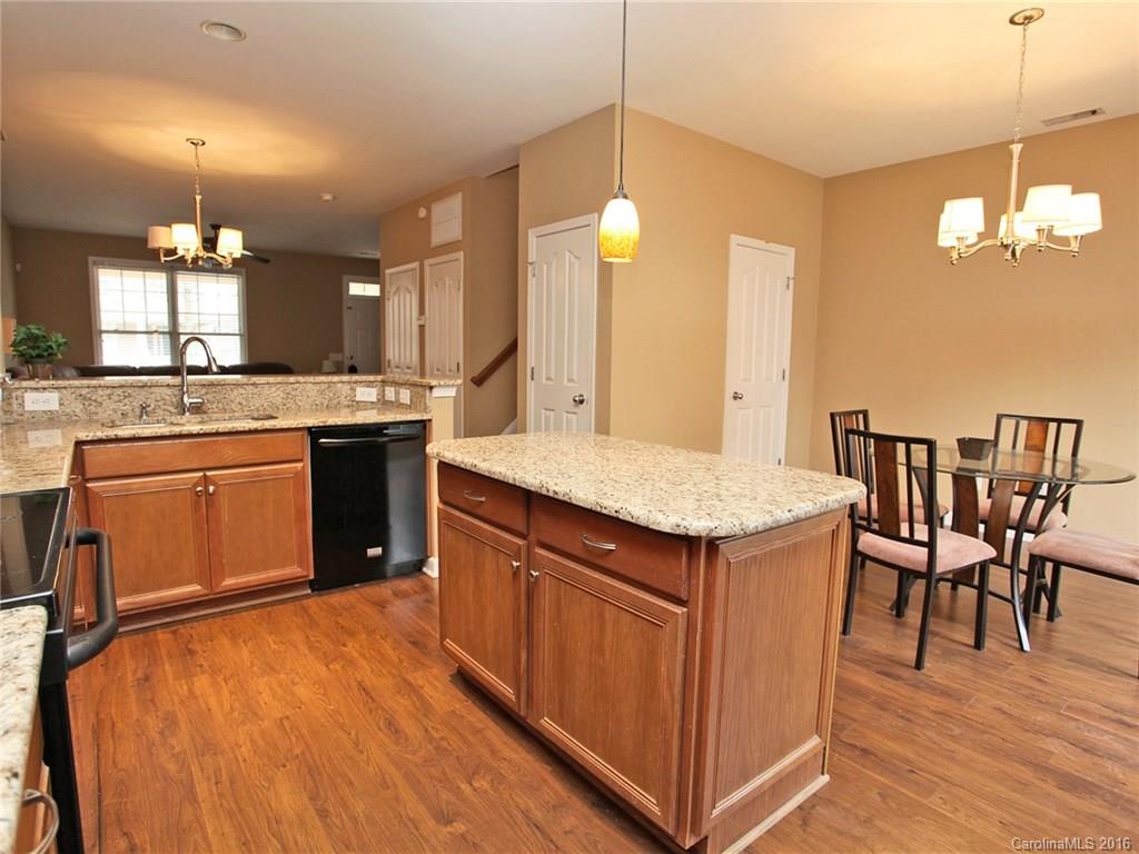 1050 Market Street, Unit 1050 Fort Mill, SC 29708 - Photo 12 of 20 a kitchen with a stove a sink dishwasher a kitchen island with wooden cabinets and floor