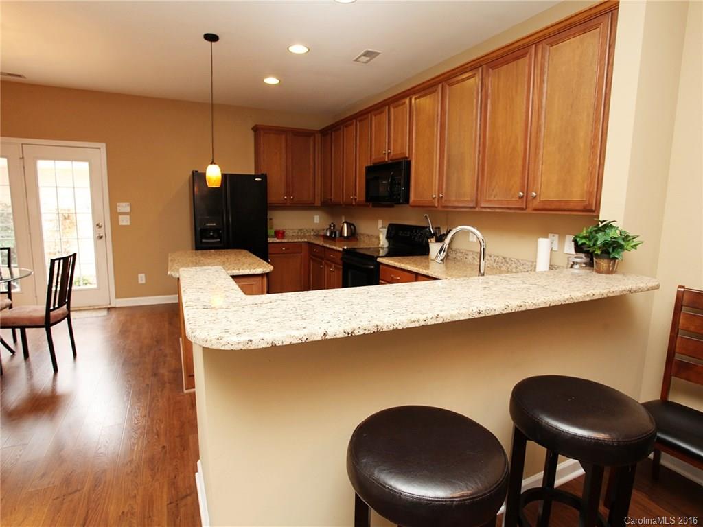 1050 Market Street, Unit 1050 Fort Mill, SC 29708 - Photo 8 of 20 a kitchen with stainless steel appliances kitchen island granite countertop a dining table chairs sink and cabinets