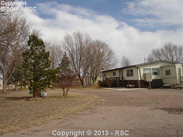 24825 Meier Road Calhan, CO 80808 - Photo 2 of 6 Shows main house and trailer in background in the trees. Also shows where mobile is connected to main house.