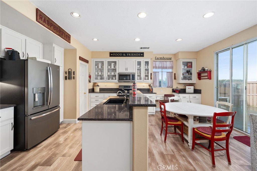 19714 Rotterdam Street Riverside, CA 92508 - Photo 11 of 46 a kitchen with stainless steel appliances kitchen island granite countertop a refrigerator a stove a sink a dining table and chairs