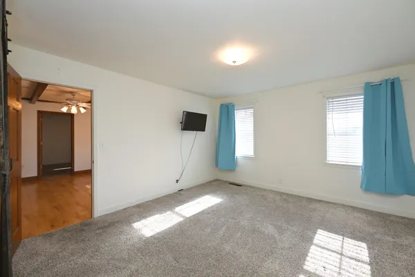 a view of an empty room with a window and wooden floor