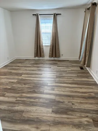 a view of a livingroom and a dining room with wooden floor and furniture