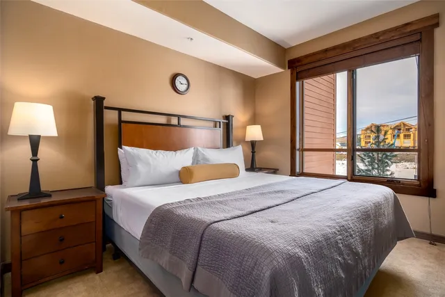 a bedroom with a bed and a lamp on dresser next to a window