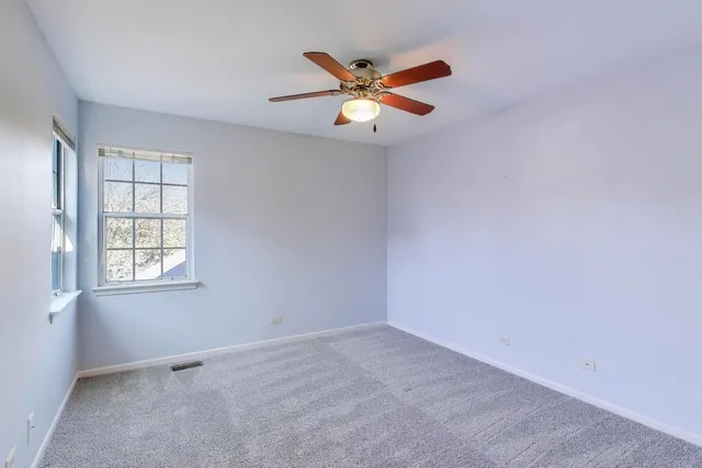 an empty room with window and ceiling fan