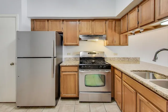 a kitchen with stainless steel appliances granite countertop a refrigerator a stove a sink and dishwasher