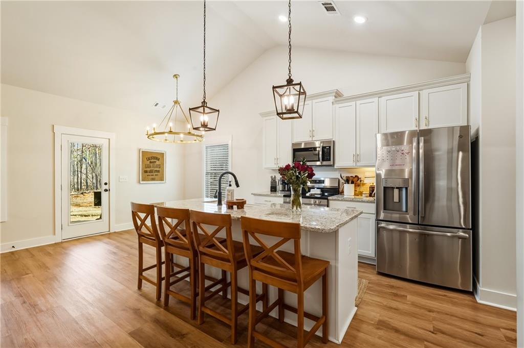 3462 Vinson Mountain Road Rockmart, GA 30153 - Photo 12 of 31 a kitchen with stainless steel appliances a dining table chairs refrigerator and microwave