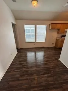a view of an empty room with wooden floor and a window