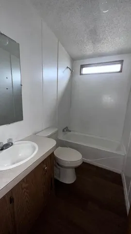 a bathroom with a granite countertop toilet a sink and a mirror