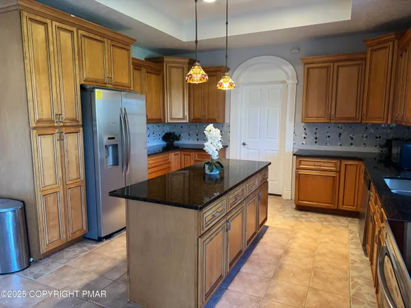 a kitchen with stainless steel appliances granite countertop a refrigerator a sink dishwasher a stove and a dining table with wooden floor