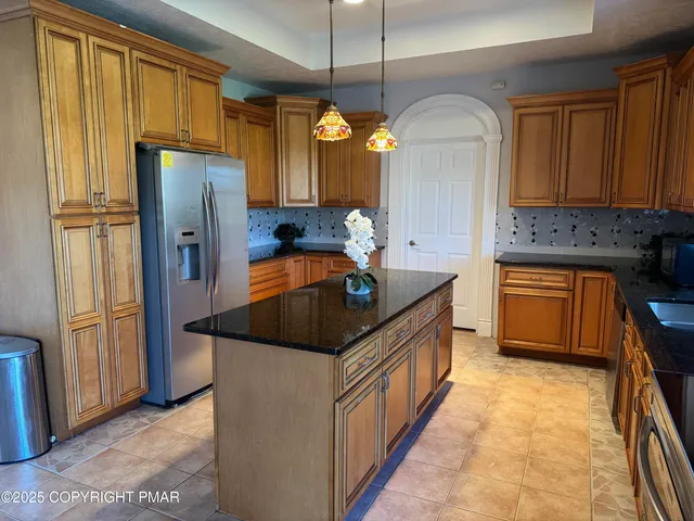 a kitchen with stainless steel appliances granite countertop a refrigerator a sink dishwasher a stove and a dining table with wooden floor