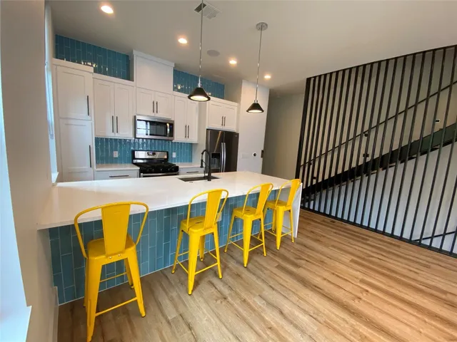 a dining room with stainless steel appliances kitchen island granite countertop a dining table chairs refrigerator and a sink