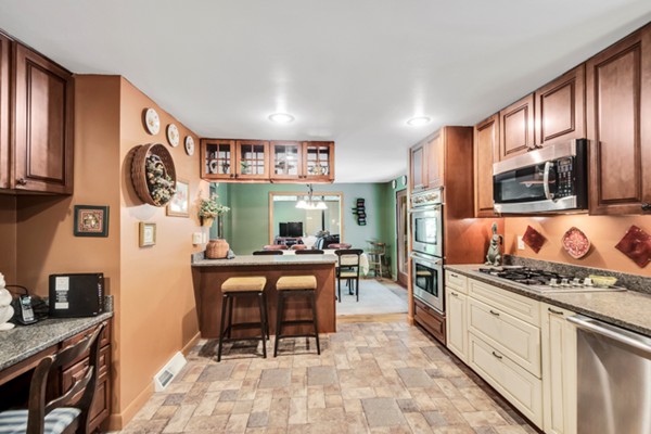 67 Chester Road Boxborough, MA 01719 - Photo 14 of 28 a kitchen with stainless steel appliances granite countertop a stove top oven a sink dishwasher a dining table and chairs with wooden floor