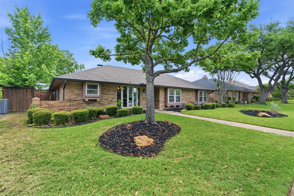 2307 Castle Rock Road Carrollton, TX 75007 - Photo 2 of 34 The property features a brick exterior, a well-maintained lawn, and mature trees in the yard
