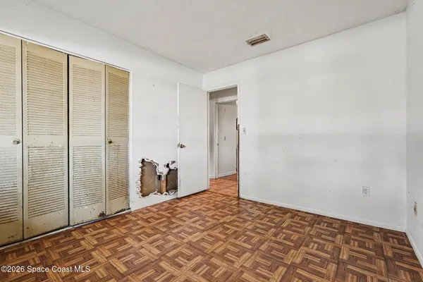 a bedroom with a bed and a walk in closet with wooden floor
