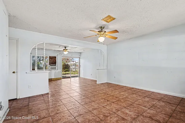 a view of an empty room with window and chandelier fan