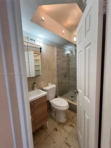 a bathroom with a granite countertop toilet a sink and a mirror