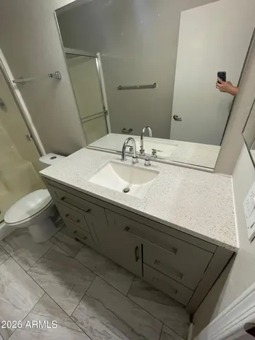 a bathroom with a granite countertop sink a toilet and a mirror