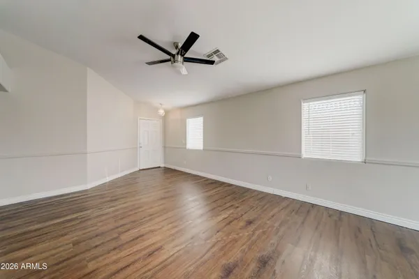 an empty room with wooden floor fan and windows