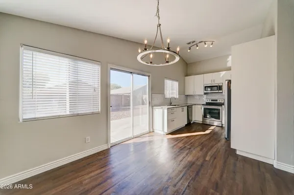 a view of a room with wooden floor chandeliers and kitchen