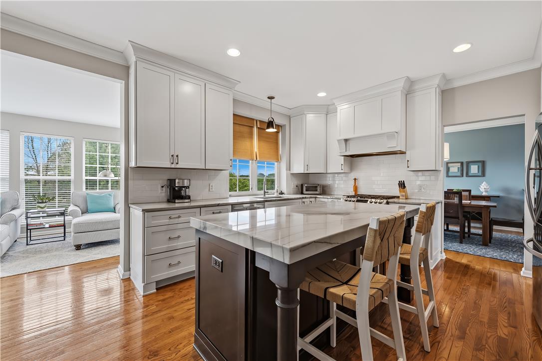 9031 Pathfinder Road Breinigsville, PA 18031 - Photo 14 of 63 A gourmet kitchen showcasing sleek white cabinetry, gleaming countertops, and rich hardwood flooring, ready for culinary creations.