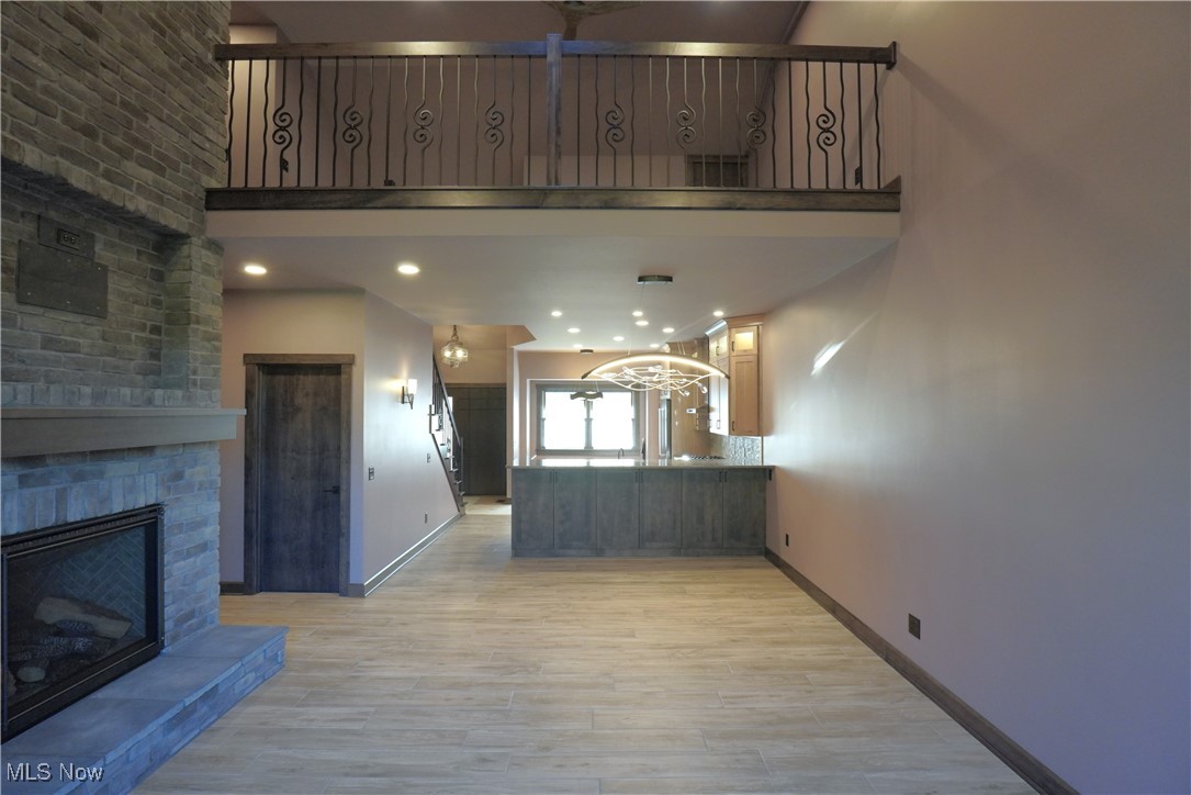 2502 Charing Cross Road Northwest Canton, OH 44708 - Photo 8 of 12 view of Loft area from the large and open Living room featuring Ceramic Plank flooring, a high ceiling, and a Brick floor to ceiling fireplace with a floating mantel and built in space for TV.