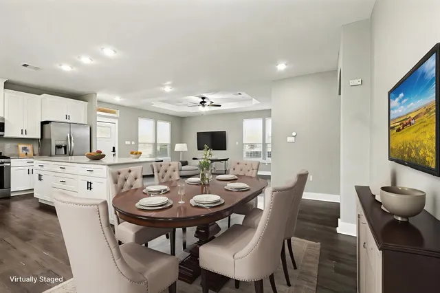 a view of an empty room and kitchen with wooden floor