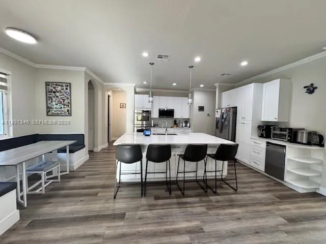 a kitchen with stainless steel appliances kitchen island granite countertop a stove a sink a dining table and chairs