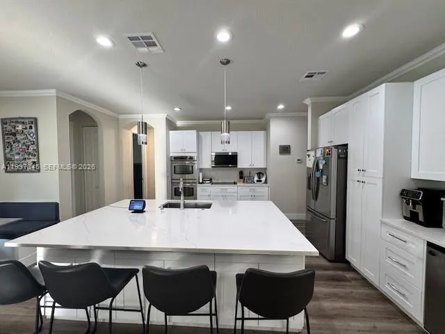 a kitchen with stainless steel appliances a dining table chairs refrigerator and microwave