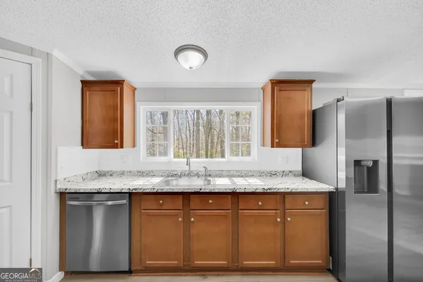 a view of kitchen with stainless steel appliances granite countertop a stove top oven a sink dishwasher and a refrigerator with wooden floor