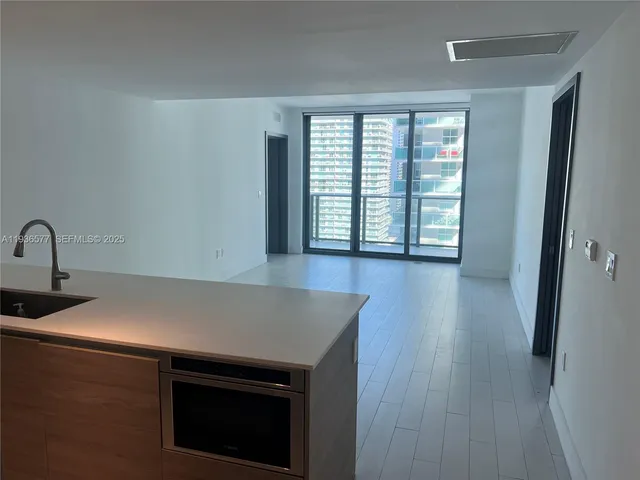 an empty room with wooden floor and windows with curtains