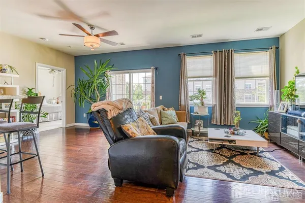 a living room with furniture large window and wooden floor