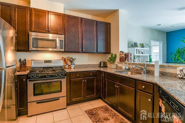 a kitchen with granite countertop wooden cabinets stainless steel appliances and a counter space