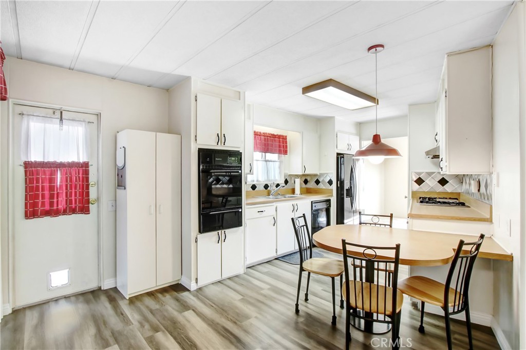 10210 Base Line Road, Unit 173 Rancho Cucamonga, CA 91701 - Photo 4 of 17 a kitchen with stainless steel appliances a refrigerator a stove a dining table and chairs